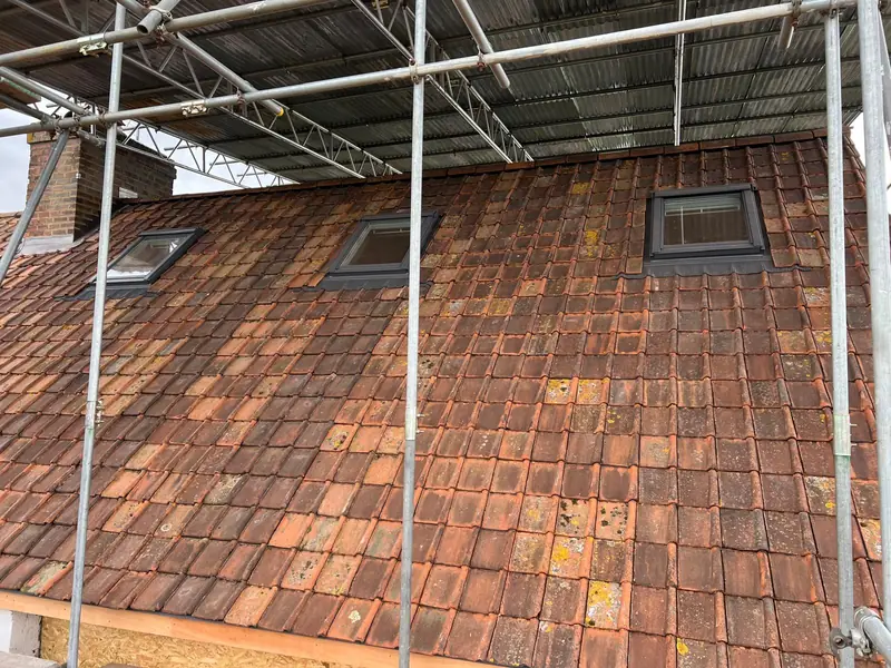 Clay-tiled roof with three roof windows, still under the scaffold
