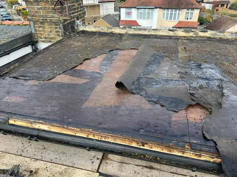 Storm-damaged flat roof with the old felt torn and peeled back