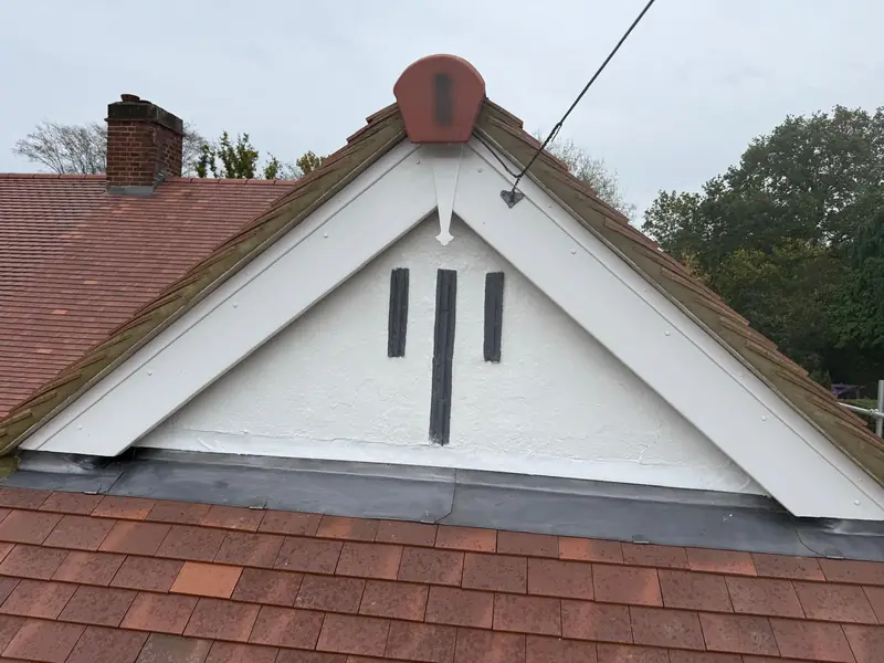 White gable above a freshly tiled roof with new lead along the joint, from a recent job