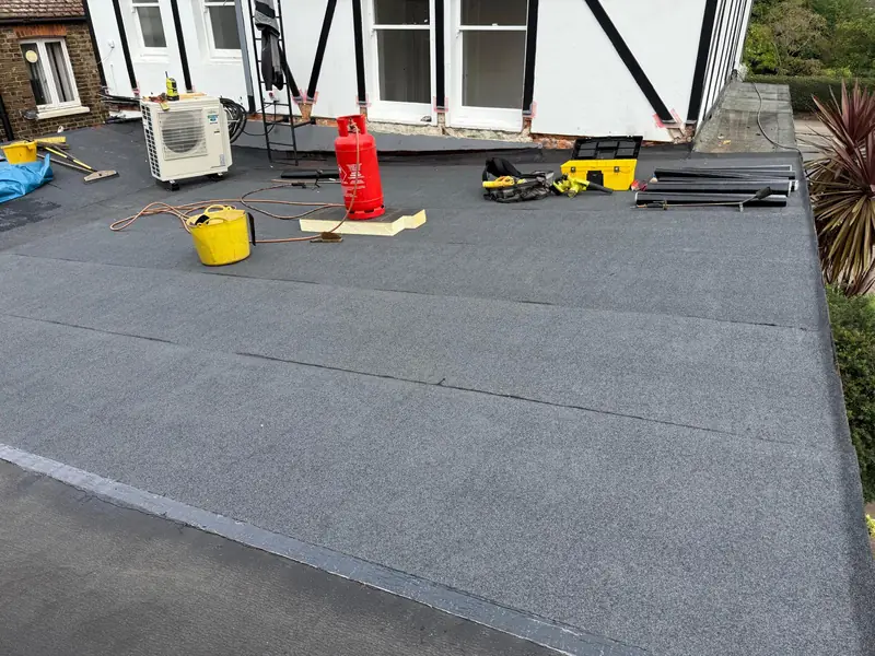 Finished felt roof on a rear extension beside a timber-framed house