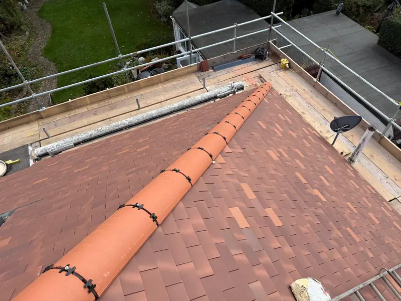 Newly tiled bungalow roof with its terracotta ridge, seen from the scaffold
