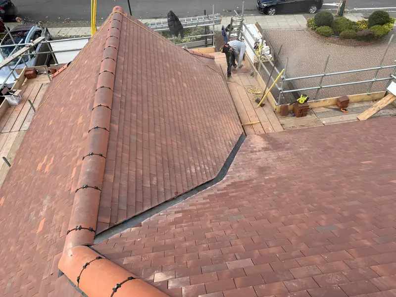 New tiled roof with a long valley and ridge, scaffolding along the front