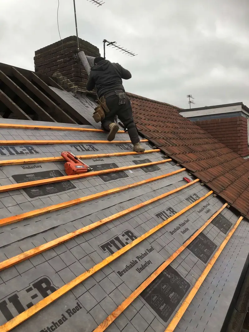 Roofer fixing battens over new underlay on a pitched roof