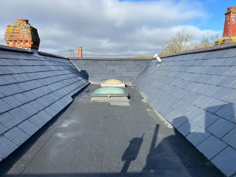 Slate roof slopes either side of a flat valley with a skylight