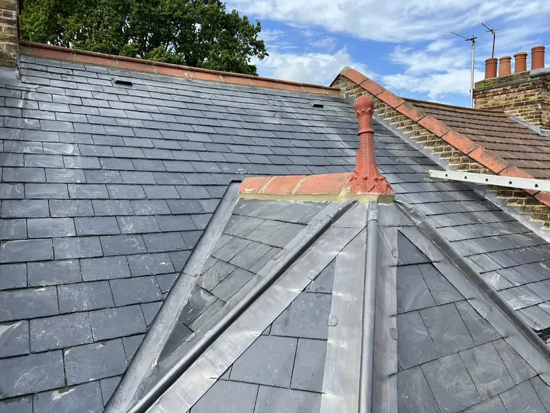 Slate roof with lead-covered hips meeting at a red finial